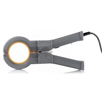 Eine graue Klemme mit einem orangefarbenen Innenring, angeschlossen an ein schwarzes Kabel, liegt auf einer weißen Oberfläche.
